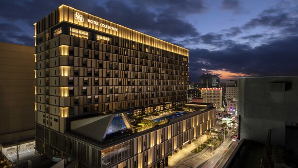 A modern hotel with a prominent "HOTEL COLLECTIVE" sign, featuring a multi-story structure with a rooftop garden and a well-lit facade. - Hotel Collective (Naha)