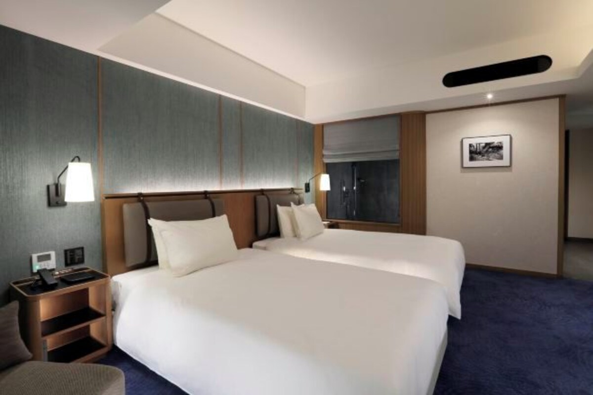 A hotel room with a large bed, bedside tables, a desk, and a chair.