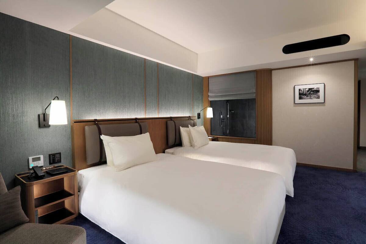 A hotel room with a large bed, a bedside table with a lamp, a small seating area, and a picture on the wall.