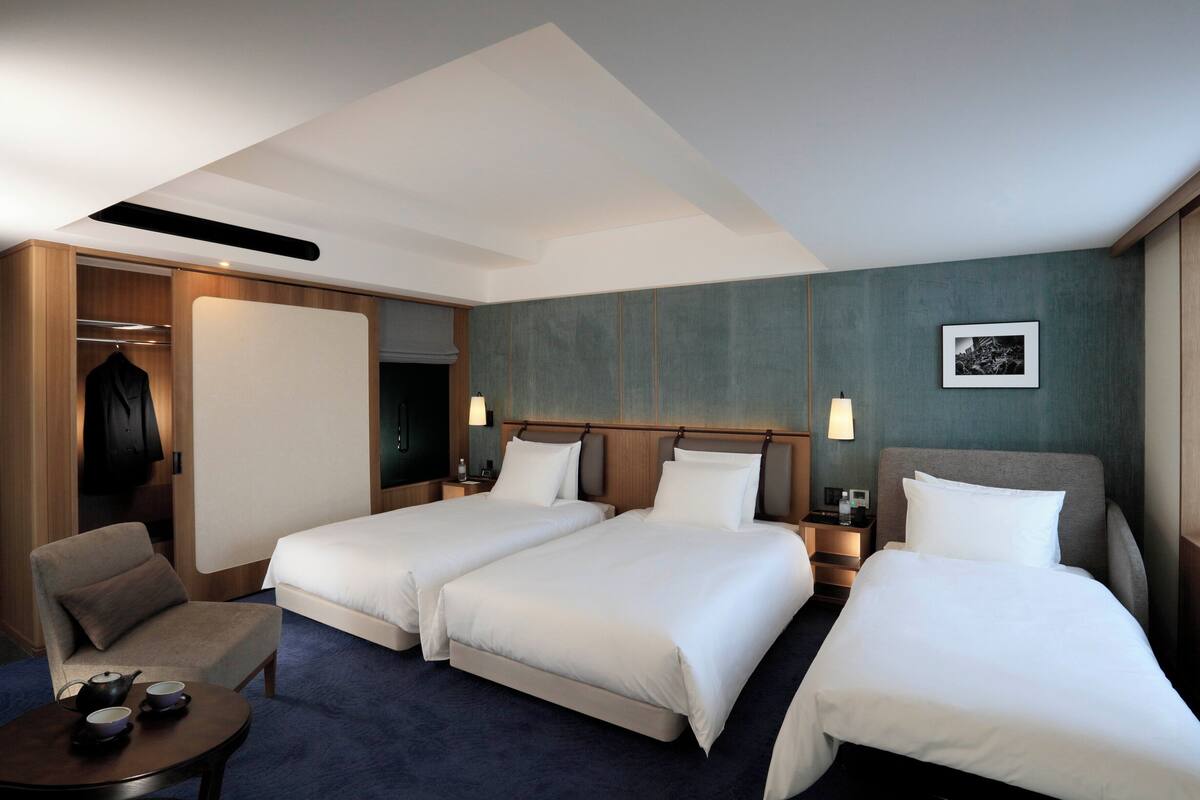 A hotel room with two beds, a seating area, and a wardrobe.