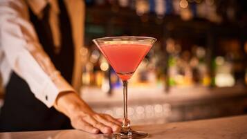 Una copa de martini sobre una barra, con un fondo borroso de botellas.