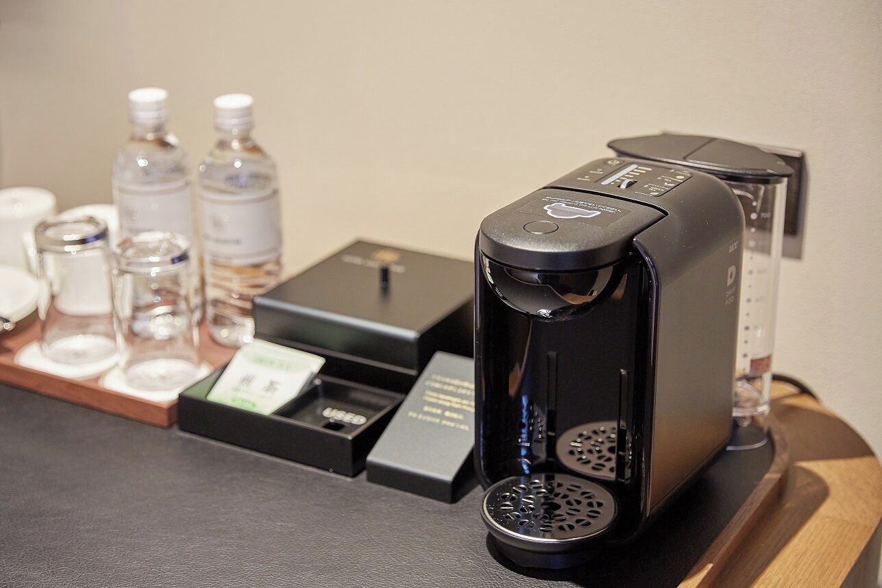 A coffee machine on a counter with a tray of condiments and a water dispenser.
