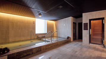 A modern indoor pool area with a wooden ceiling, a glass barrier, and a bench.