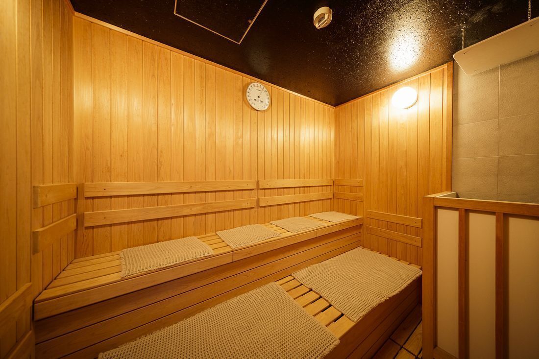 A wooden sauna with benches and a clock on the wall.