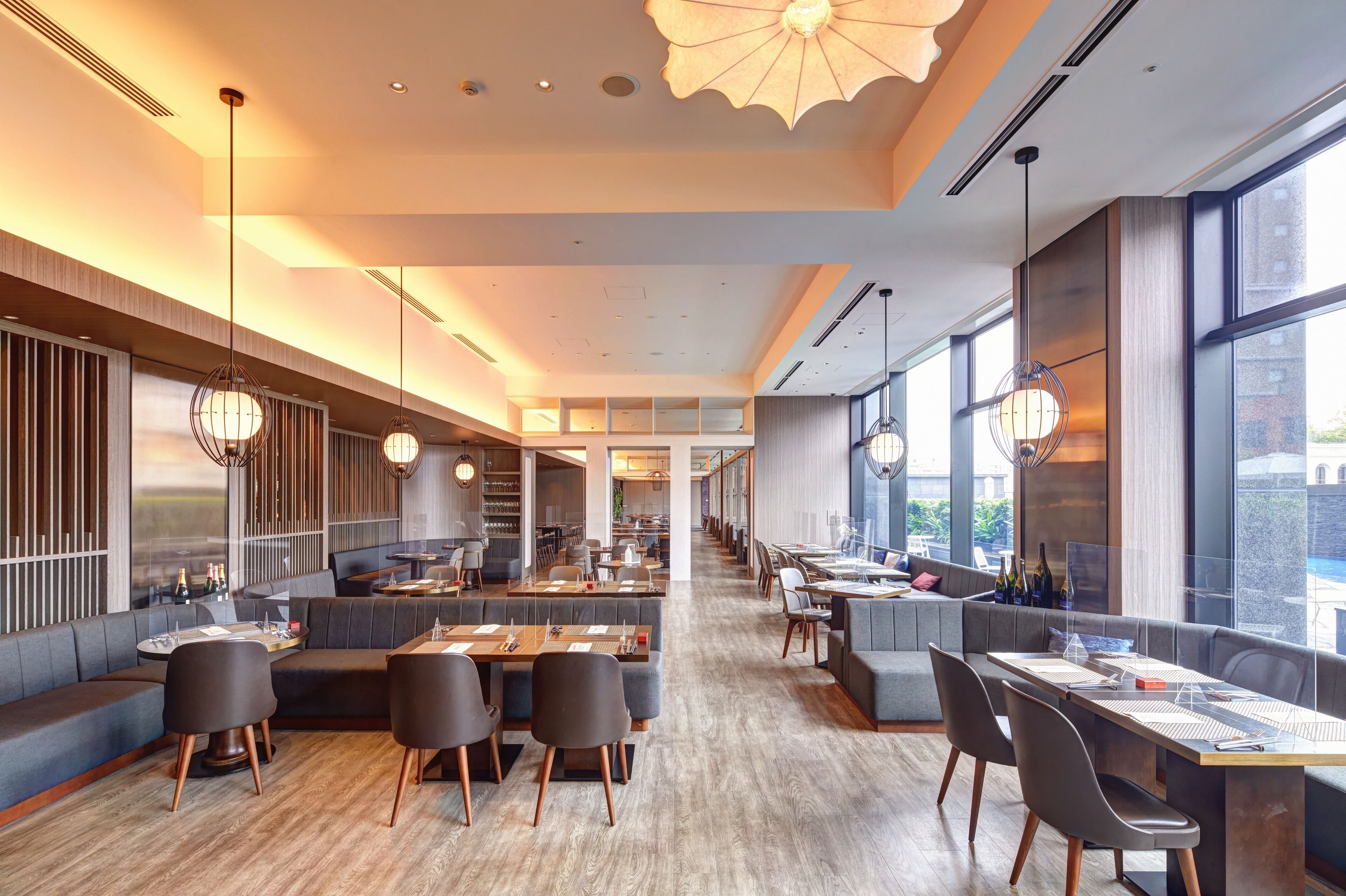 Un restaurant spacieux avec de hauts plafonds, un éclairage moderne et de grandes fenêtres offrant une vue sur la ville.