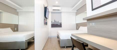 Une chambre d’hôtel moderne avec deux lits, un bureau, une chaise et une affiche représentant un paysage urbain.