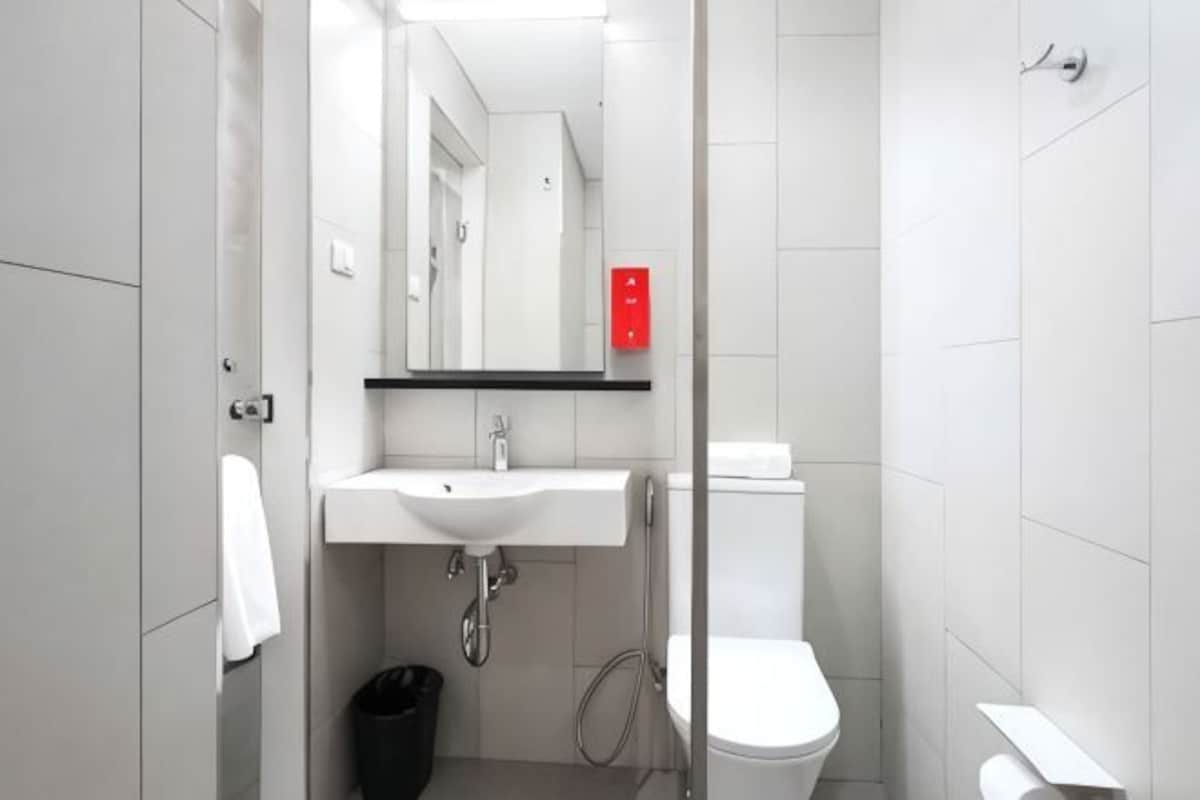 Un baño con lavamanos, espejo y retrete blanco.
