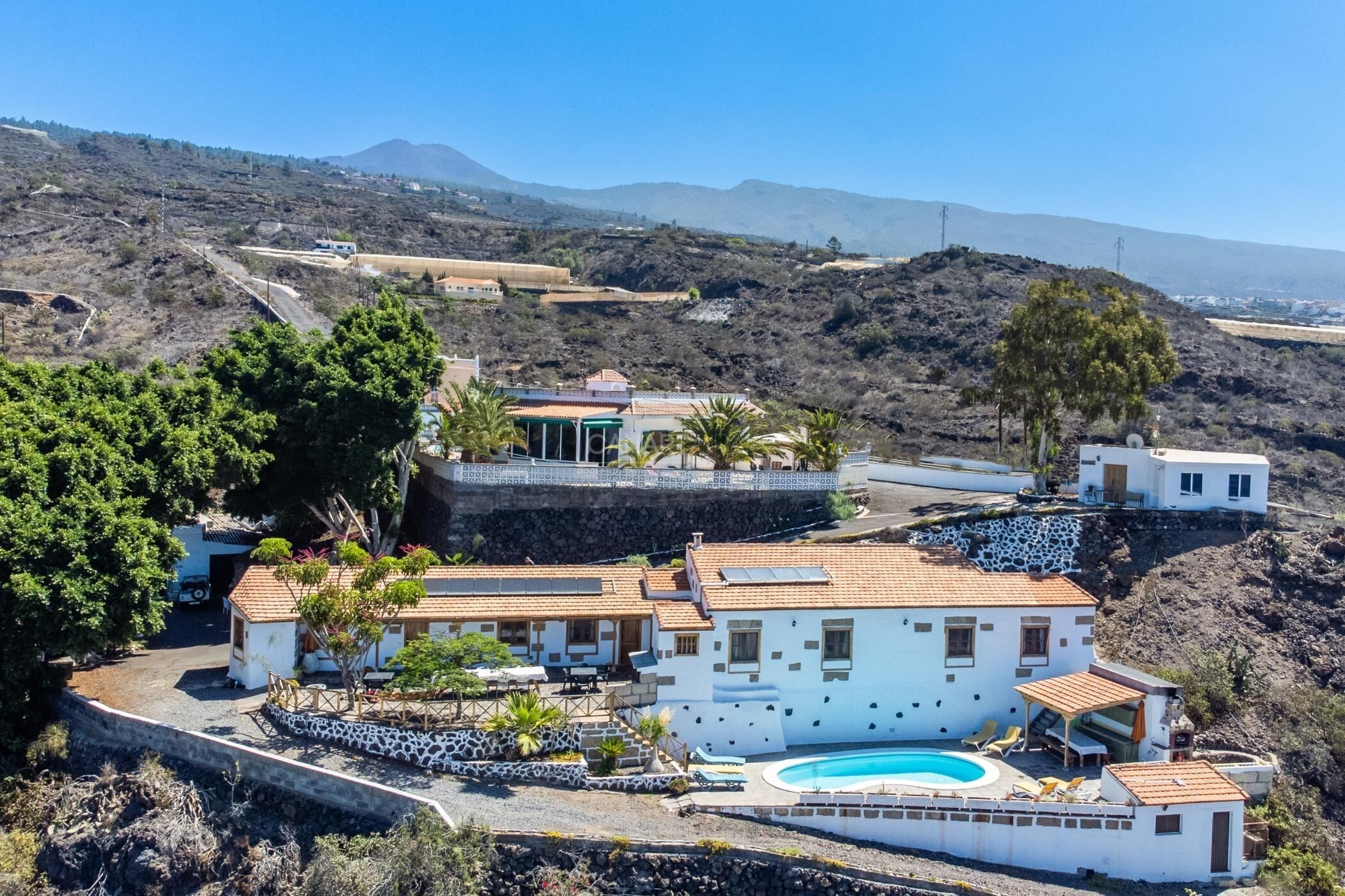 Una villa costera con piscina, varias habitaciones y vistas del paisaje circundante.