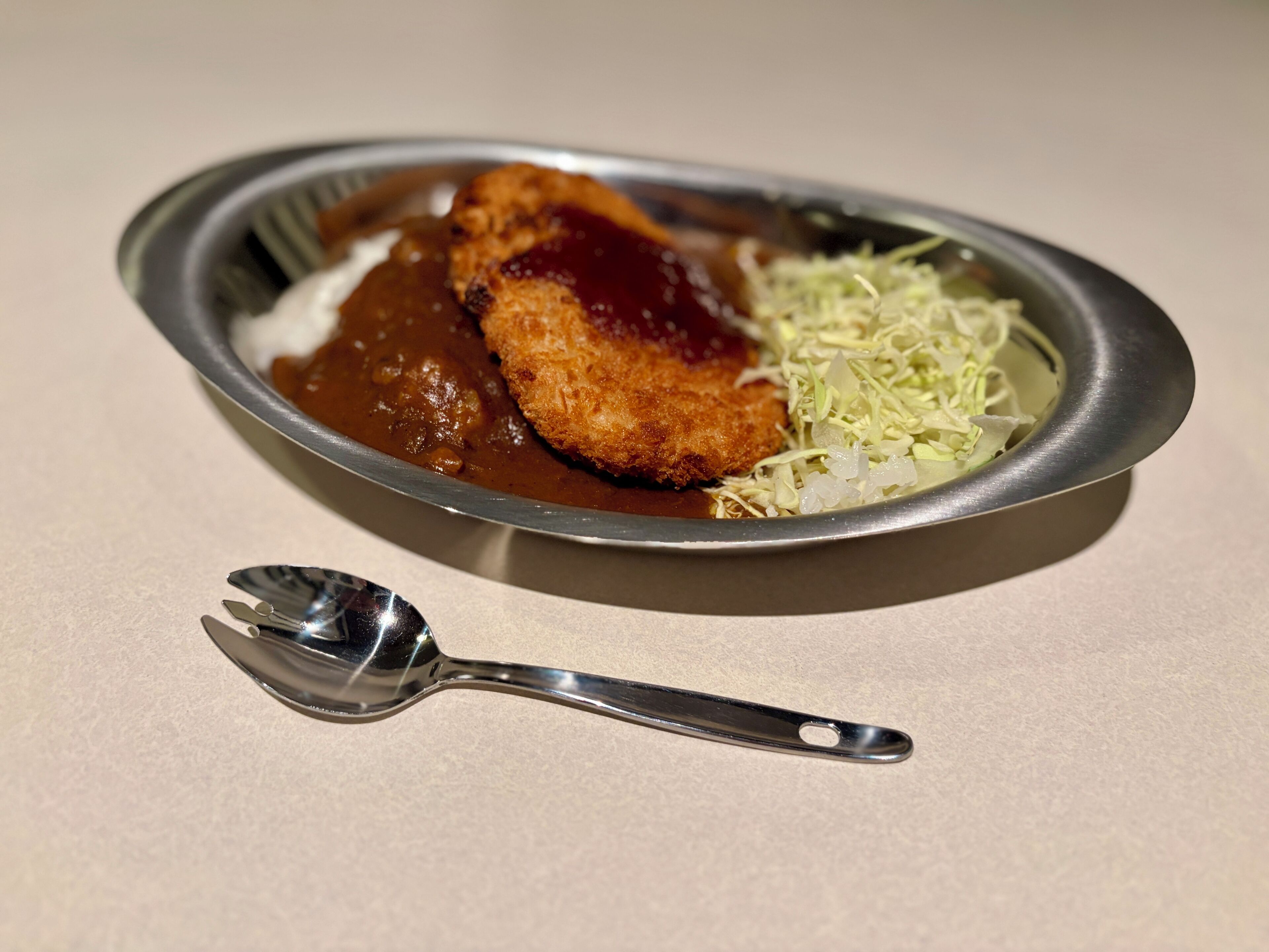 A plate with a breaded cutlet, a side of sauerkraut, and a spoon.