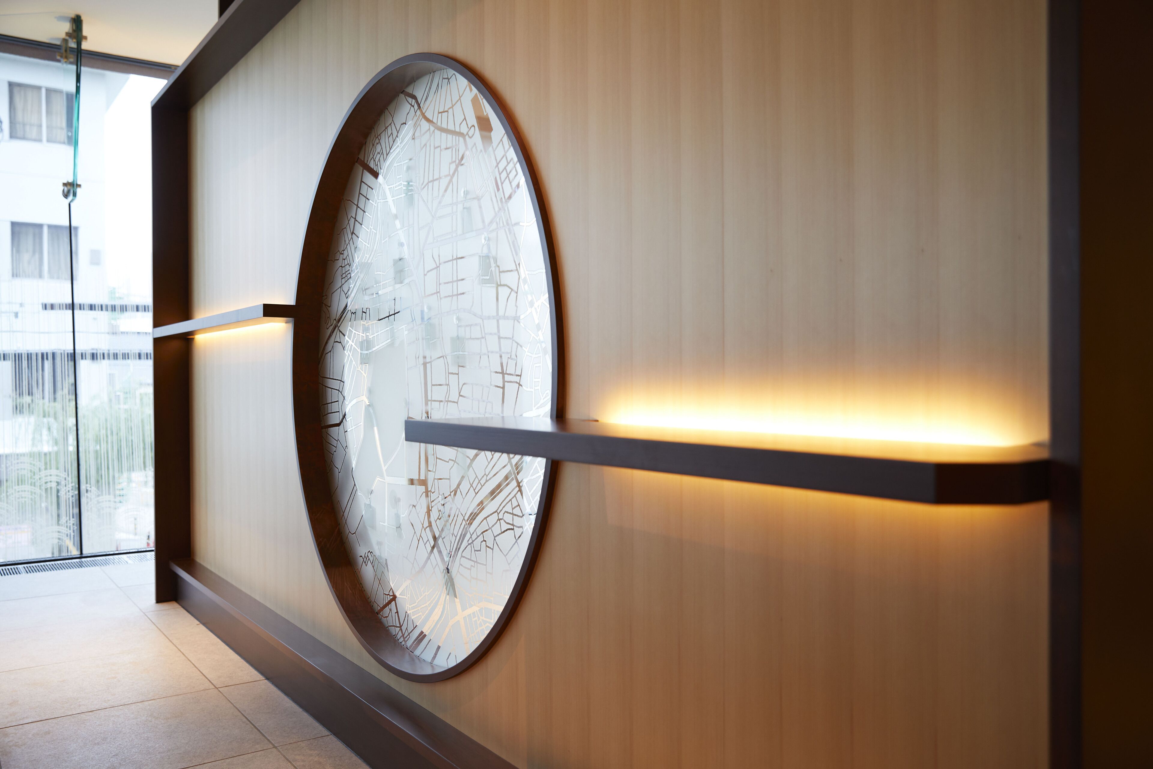 A modern interior with a large circular wall art piece, a wooden panel wall, and a glass door leading to an outdoor area.