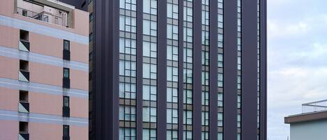 Un bâtiment moderne à la façade plate, doté de grandes fenêtres et d’un espace de stationnement à l’avant.