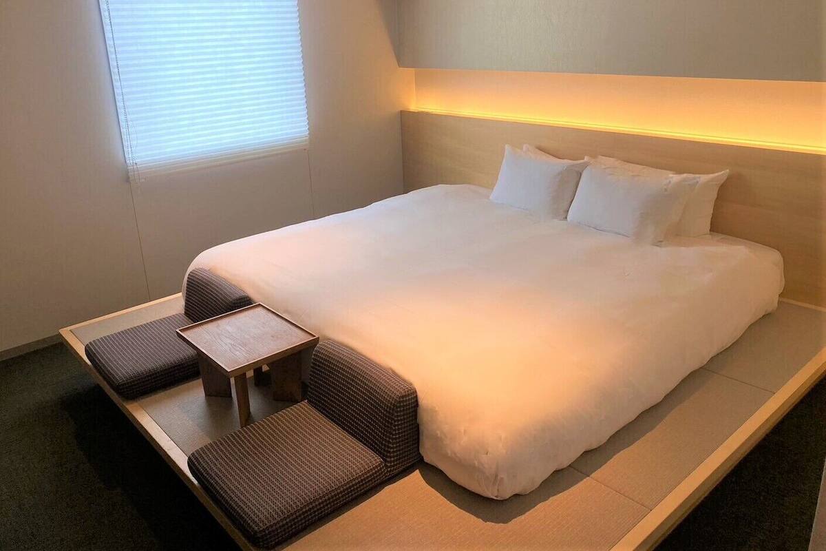Ein modernes Hotelzimmer mit einem großen Bett, einem kleinen Tisch und zwei Stühlen.