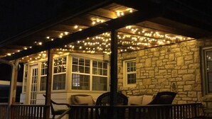A covered outdoor seating area with stone walls and string lights.