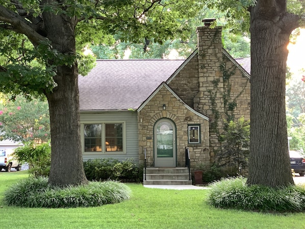 A stone house with a green door, a chimney, and a small porch.
