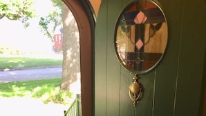 A green door with a circular window and a brass knocker.