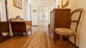 A hallway with a patterned rug, wooden furniture, and a door in the background.