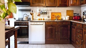 A kitchen with wooden cabinets, a stove, a dishwasher, and various kitchen utensils.
