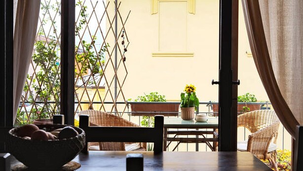 A dining area with a table, chairs, and a window with a view of the street and buildings.