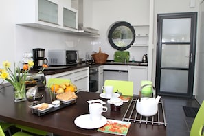 A modern kitchen with white cabinets, a round window, and a dining area with a table set for breakfast.