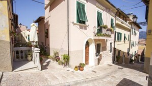 A narrow street with buildings featuring balconies and potted plants. - Two-room apartment Piazza al Fico 2/4 Beds in the historic center of Portoferraio (PORTOFERRAIO)