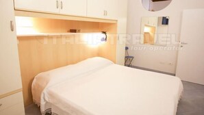A bedroom with a bed, a wardrobe, a mirror, and a small circular window. - Two-room apartment Piazza al Fico 2/4 Beds in the historic center of Portoferraio (PORTOFERRAIO)