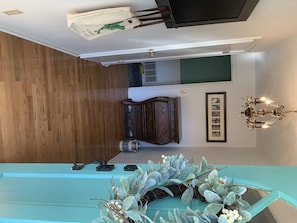 A stylish space with a wooden floor, featuring a cabinet, a framed picture, and a chandelier.