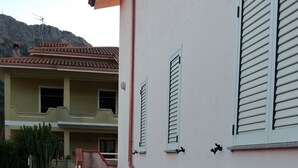 Un bâtiment dont la partie inférieure est en pierre et la partie supérieure est blanche, avec un escalier et deux fenêtres dotées de volets.