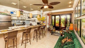A modern kitchen with a central island, bar stools, and a dining area with a green sofa. - 7 BRD  "The Coral Penthouse" w/360° | Beach | AC All Rm (Rio de Janeiro)