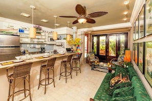A modern kitchen with a central island, bar stools, and a dining area with a green sofa. - 7 BRD  "The Coral Penthouse" w/360° | Beach | AC All Rm (Rio de Janeiro)