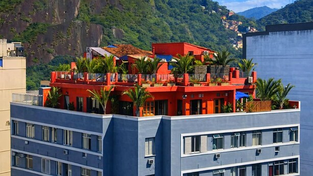 Un immeuble à plusieurs étages doté de balcons, entouré de verdure et de montagnes.