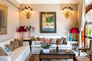 A living room with a sofa, a coffee table, two wall-mounted lamps, and a framed artwork.