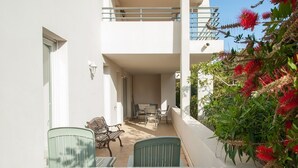 Ein Balkon mit Tisch, Stühlen, einer Tür und einem Geländer.
