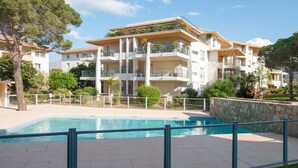 Ein modernes Mehrfamilienhaus mit Schwimmbad, Balkonen und einer Steinmauer.