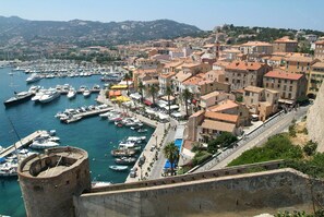 A coastal town with a historic harbor, stone buildings, and a prominent tower.