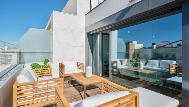 A modern rooftop terrace with wooden furniture, a glass table, and a view of the cityscape and a red bridge. - Lovage Gray Apartment, Benfica, Lisbon (Lisboa)