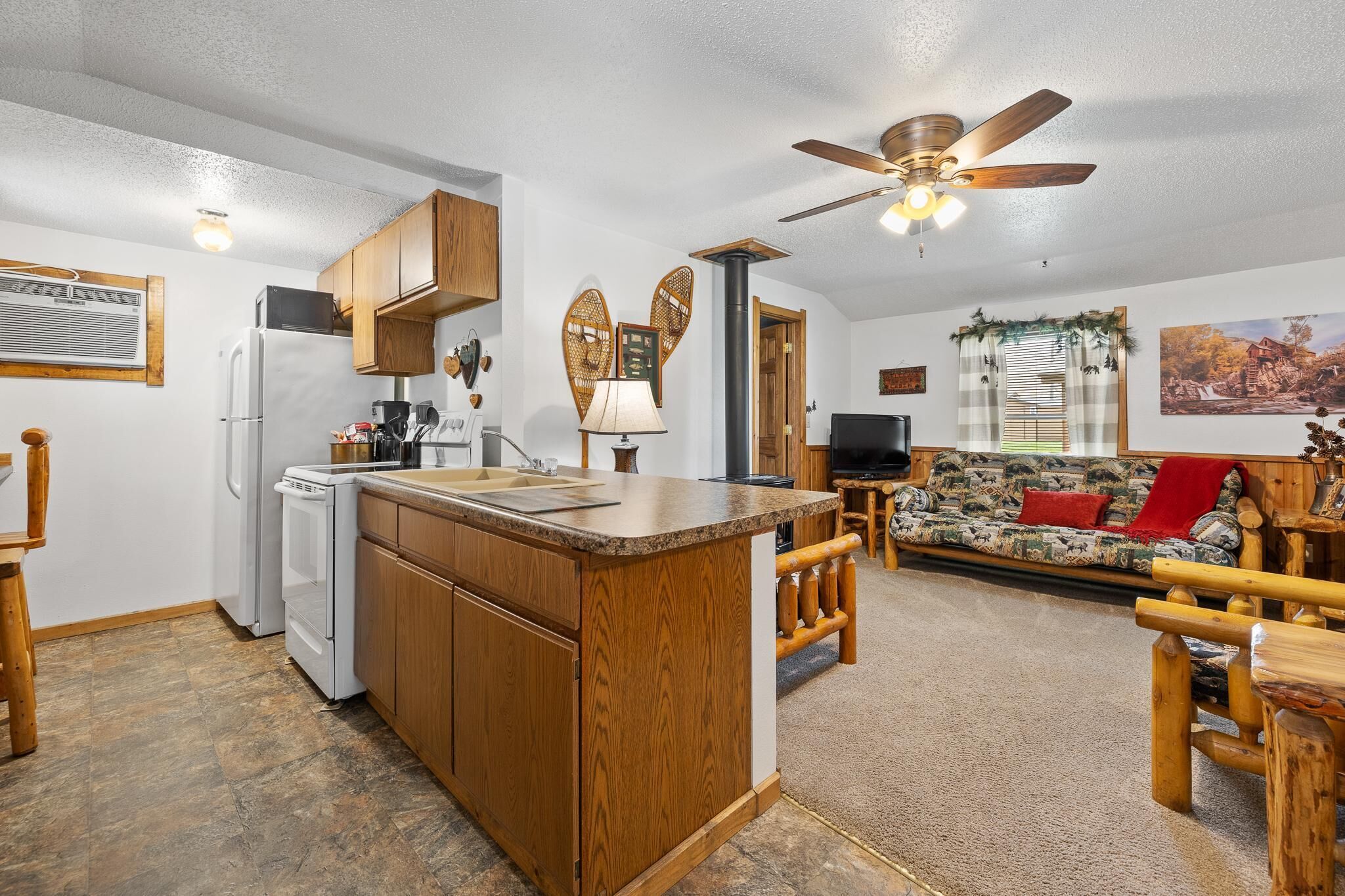 A compact kitchen with wooden cabinets, a built-in island, and a ceiling fan.