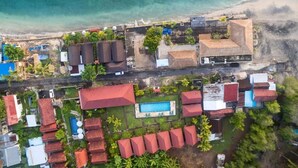 An aerial view of a coastal resort with multiple buildings, a swimming pool, and a beach. - Rijet Villa Beach & Restaurant (Penida Island)