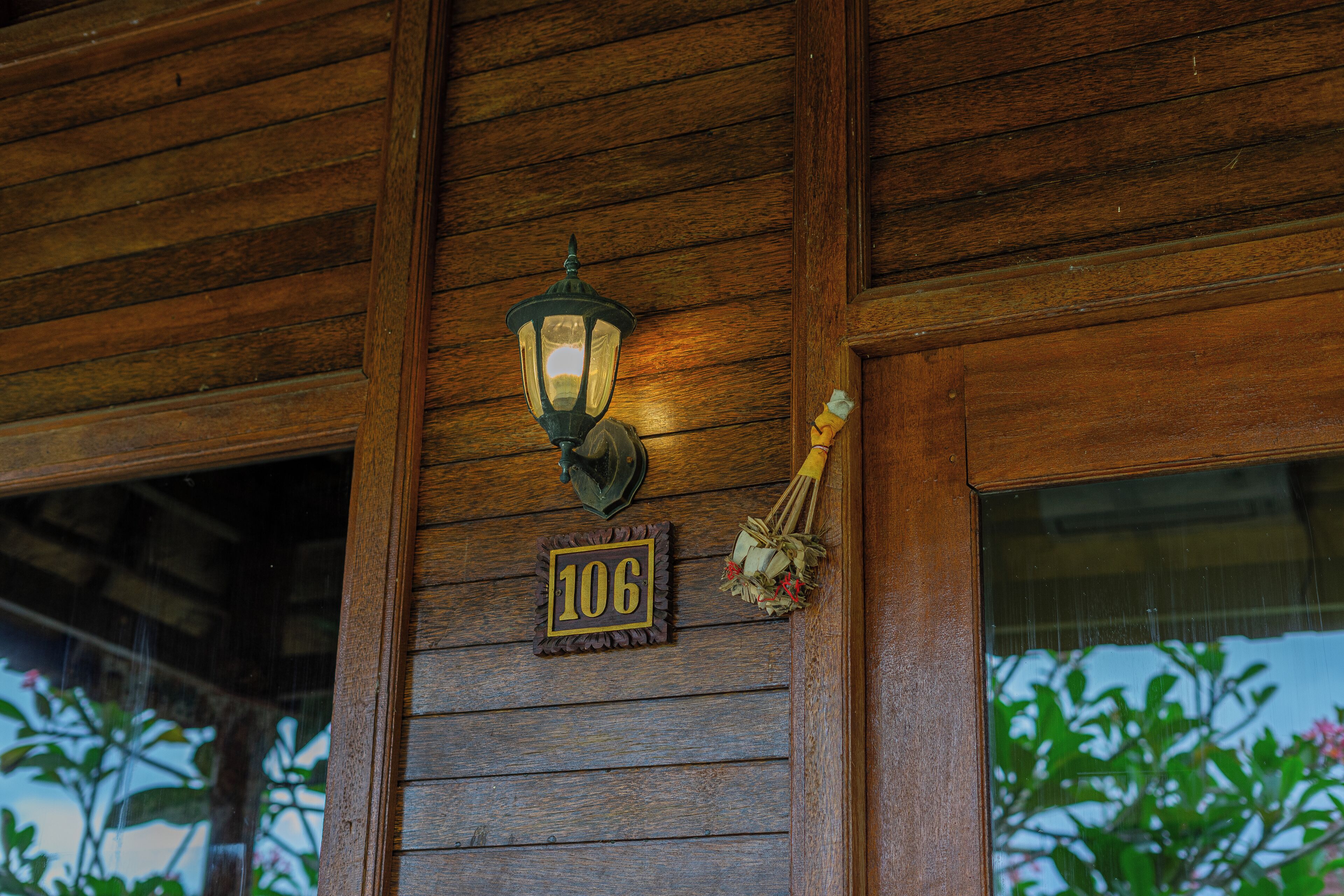 Ein Holzhaus mit einer Nummernschild '106' und einer Wandleuchte.