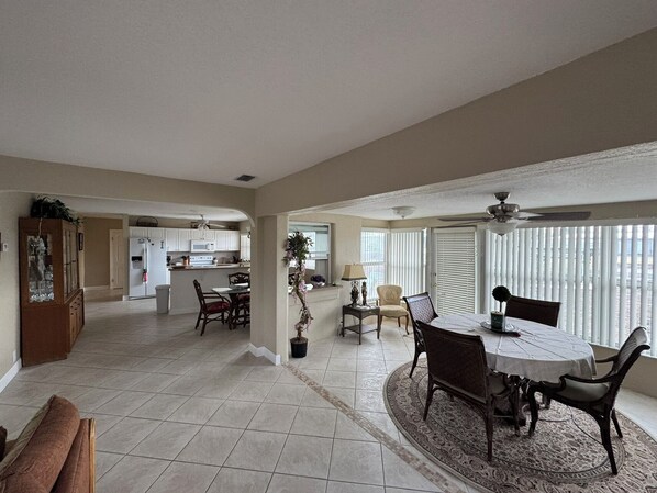 A spacious living area with a dining table, chairs, a sofa, and a kitchen in the background. - Fishing/ Boating Canal Front Home (Englewood)