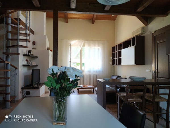 A modern kitchen with a dining area, a staircase, and a vase with flowers on the table.