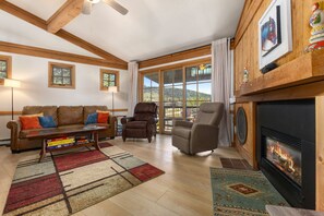 A cozy living room with a fireplace, leather sofas, and a large window offering a scenic view. - 2 Bedrooms + Loft, Balcony w/ Great Views - Hot Tub - 30, Night Rentals + EZCancel (Steamboat Springs)