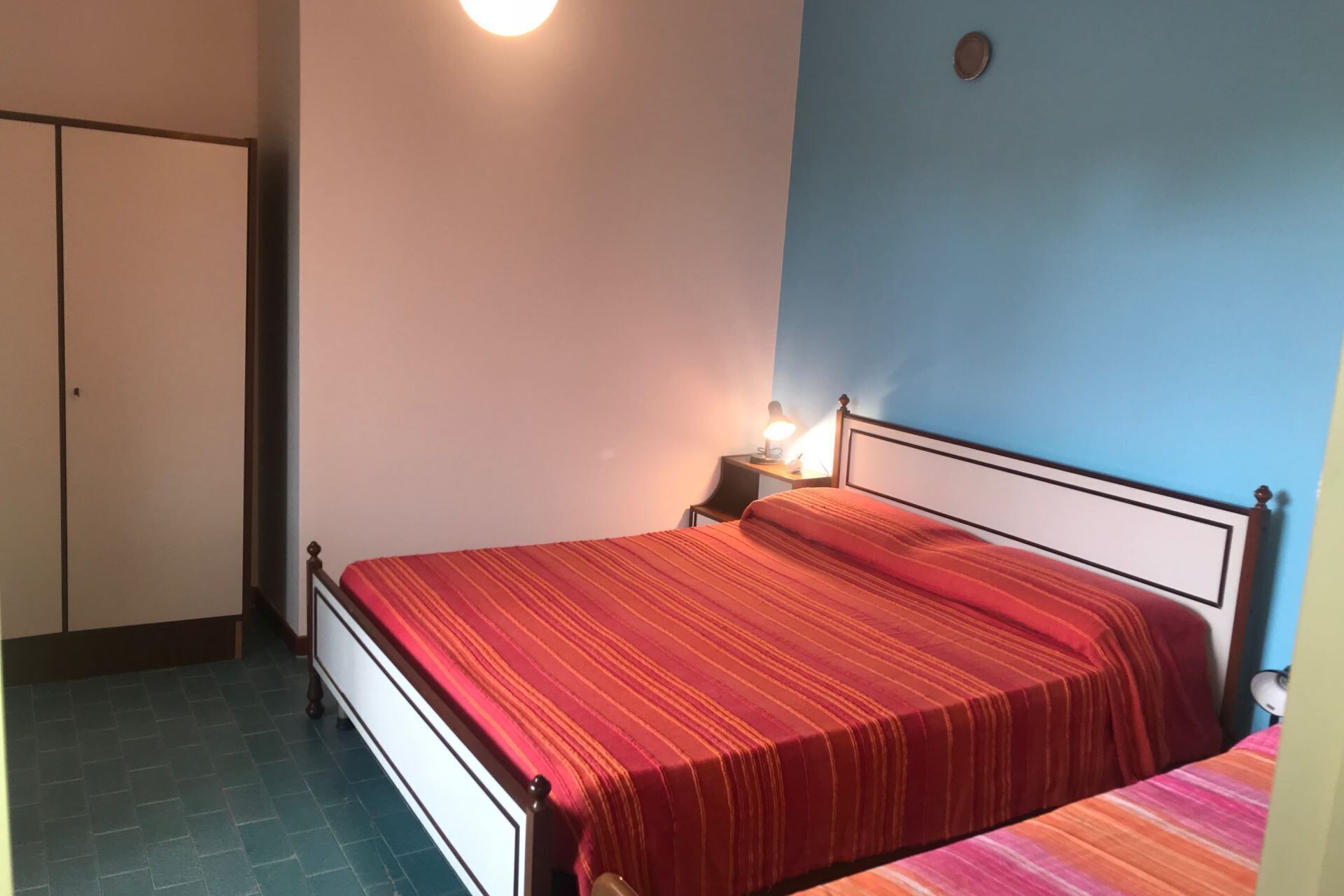 Une chambre à coucher avec un lit, une table de chevet, une lampe et une armoire.