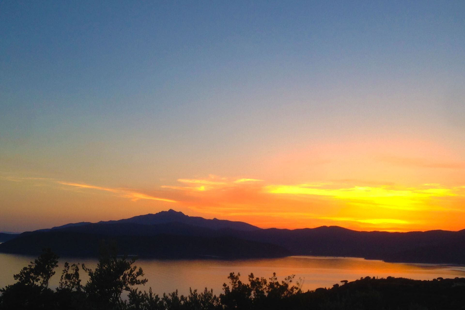 A sunset over a lake with mountains in the background.