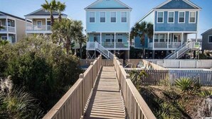 A wooden boardwalk leading to a row of beach houses with balconies and railings. - 5 Bedroom & 5 Bath Beachfront House w/ Private Pool, Hot Tub & Beach Boardwalk! (Surfside Beach)