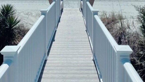 A wooden boardwalk leading to the beach with white railings and a clear view of the ocean. - 5 Bedroom & 5 Bath Beachfront House w/ Private Pool, Hot Tub & Beach Boardwalk! (Surfside Beach)