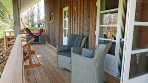 Eine Holzterrasse mit Korbmöbeln und einer Hängematte.