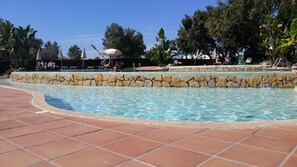 Una piscina amb mur de pedra i zona de solàrium enrajolat.