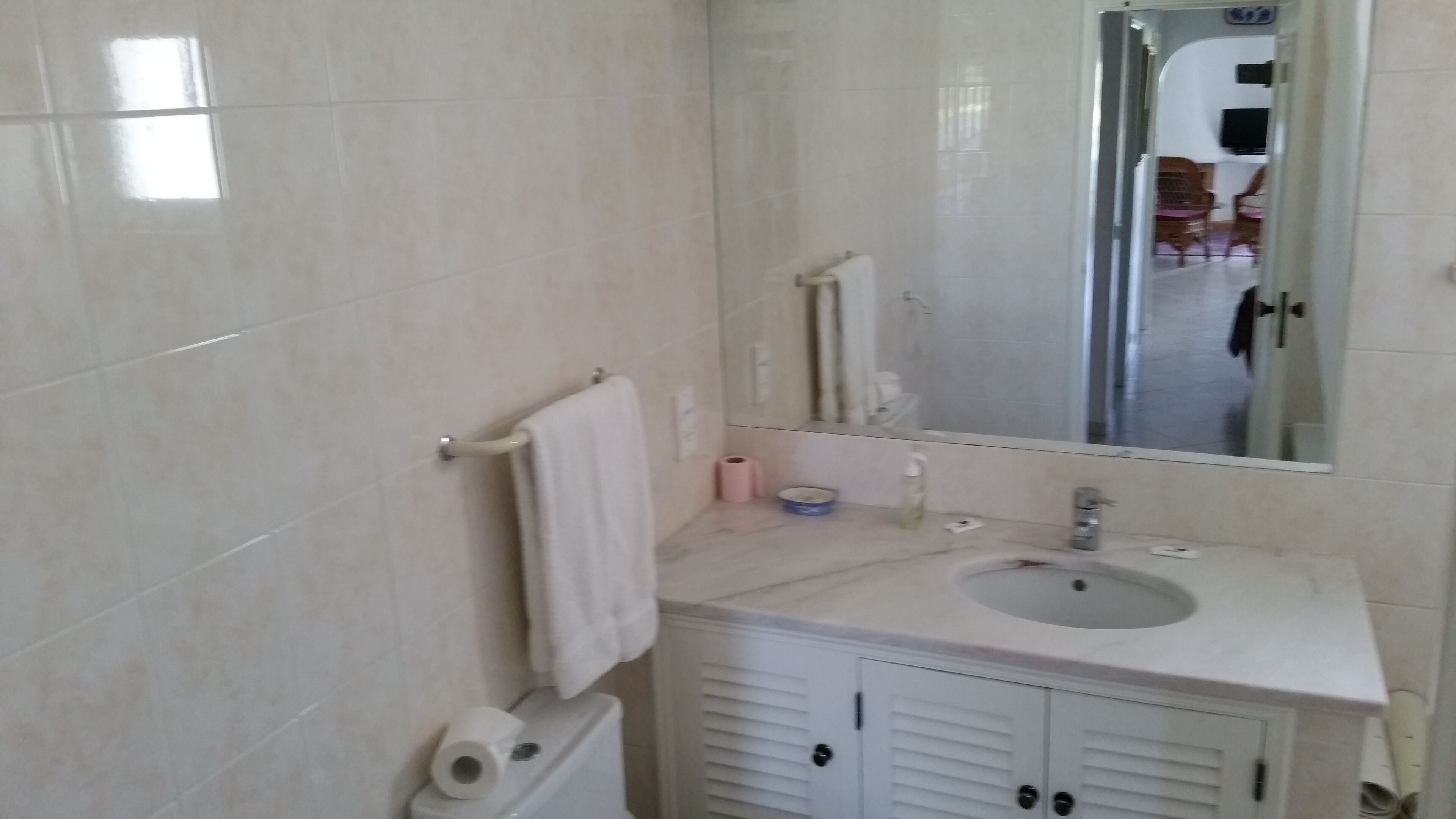 Une salle de bain avec un lavabo blanc, un miroir et un meuble.