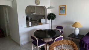 Espai vital reduït amb cuina, zona de dinar i una taula petita amb cadires.