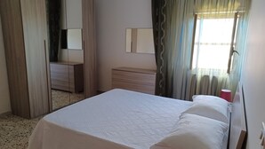A bedroom with a bed, a dresser, a mirror, and a window with curtains.